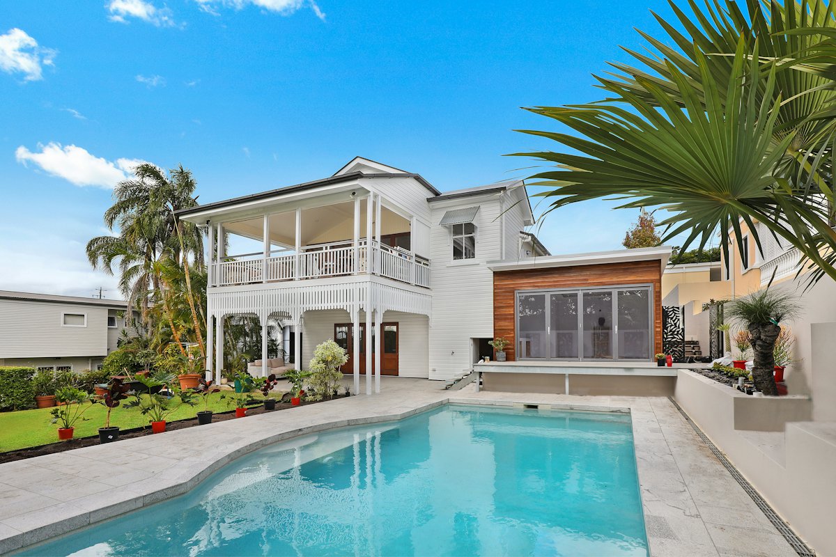 Casa branca com extensão de madeira e piscina no jardim