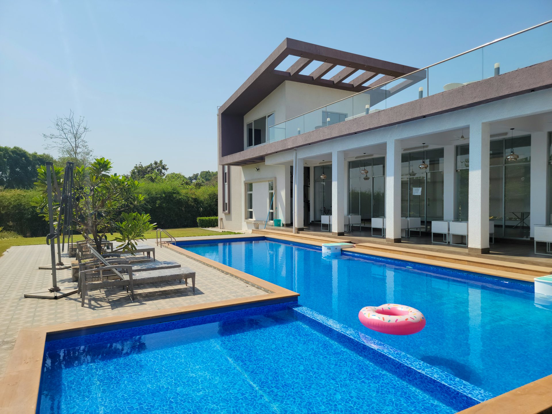Piscina com deck de madeira e espreguiçadeiras cercada por vegetação tropical