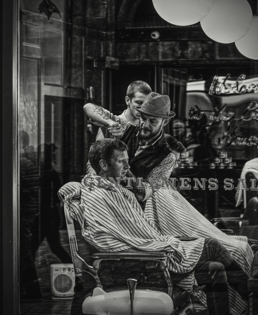Barbeiro cortando cabelo em salão antigo