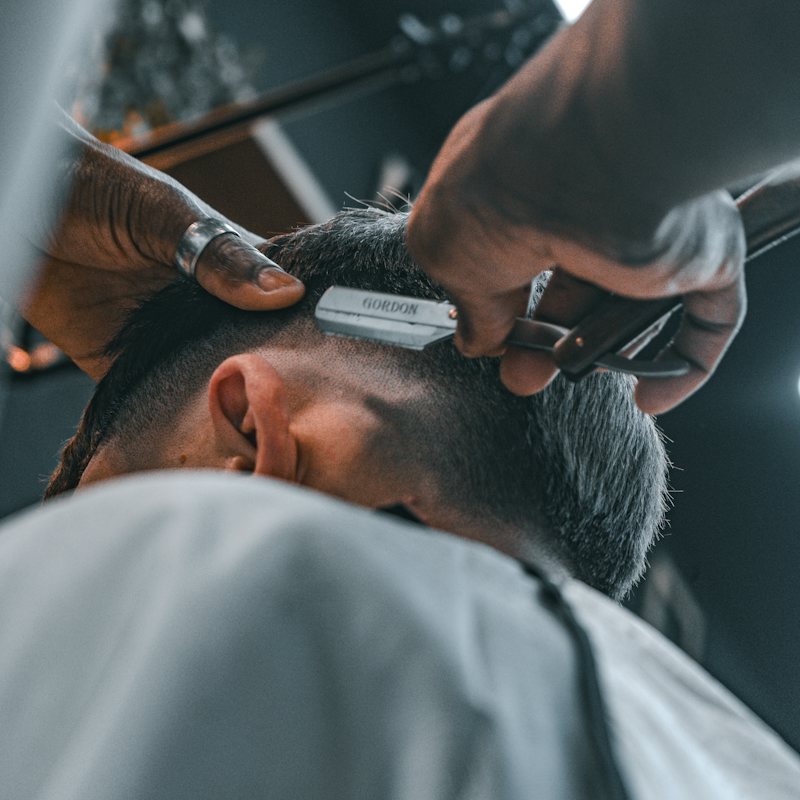 Barbeiro aparando cabelo com máquina e pente