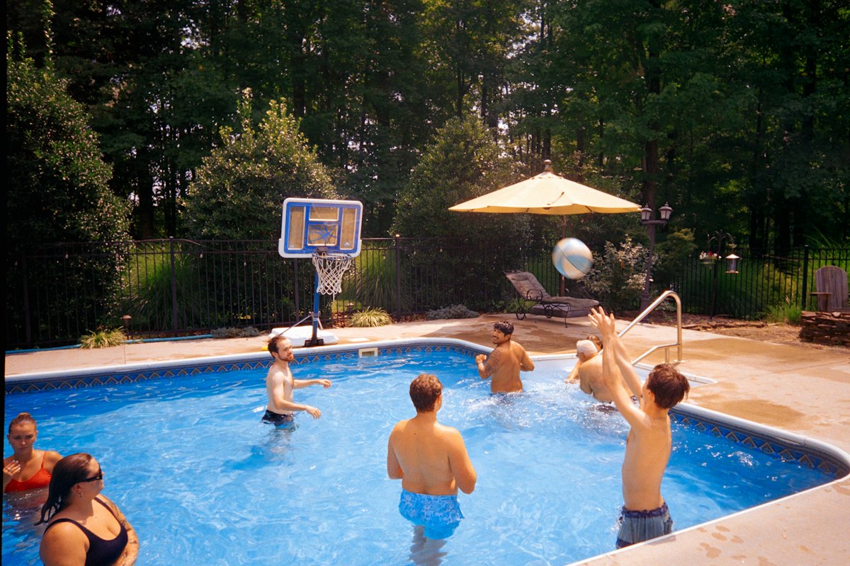 Pessoas jogando vôlei dentro de uma piscina no quintal