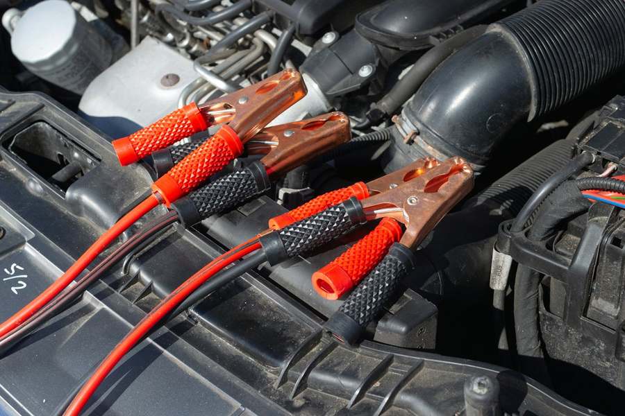 Cabos de chupeta vermelhos e pretos presos à bateria no cofre do motor