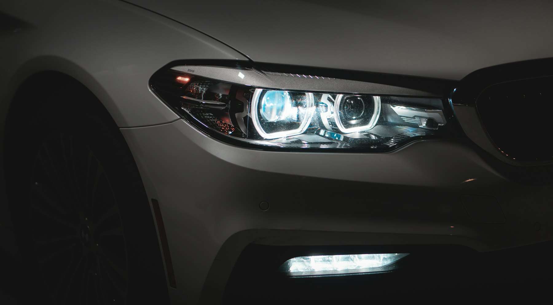Farol de LED aceso em um carro cinza, no escuro
