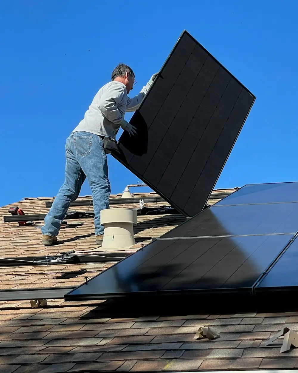 Instalador posicionando um módulo solar no telhado